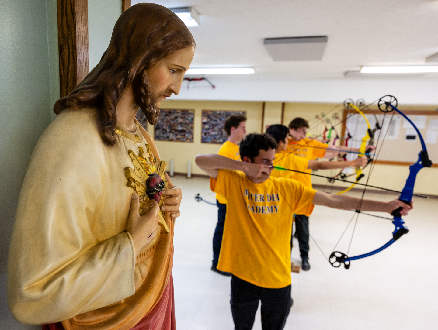 Members of the Mater Dei Academy practice in the basement of the Mary Immaculate Church in Omaha, where a statue of Jesus watches over their range.