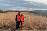 A father and daughter pose in a field during fall hunting season in Nebraska.