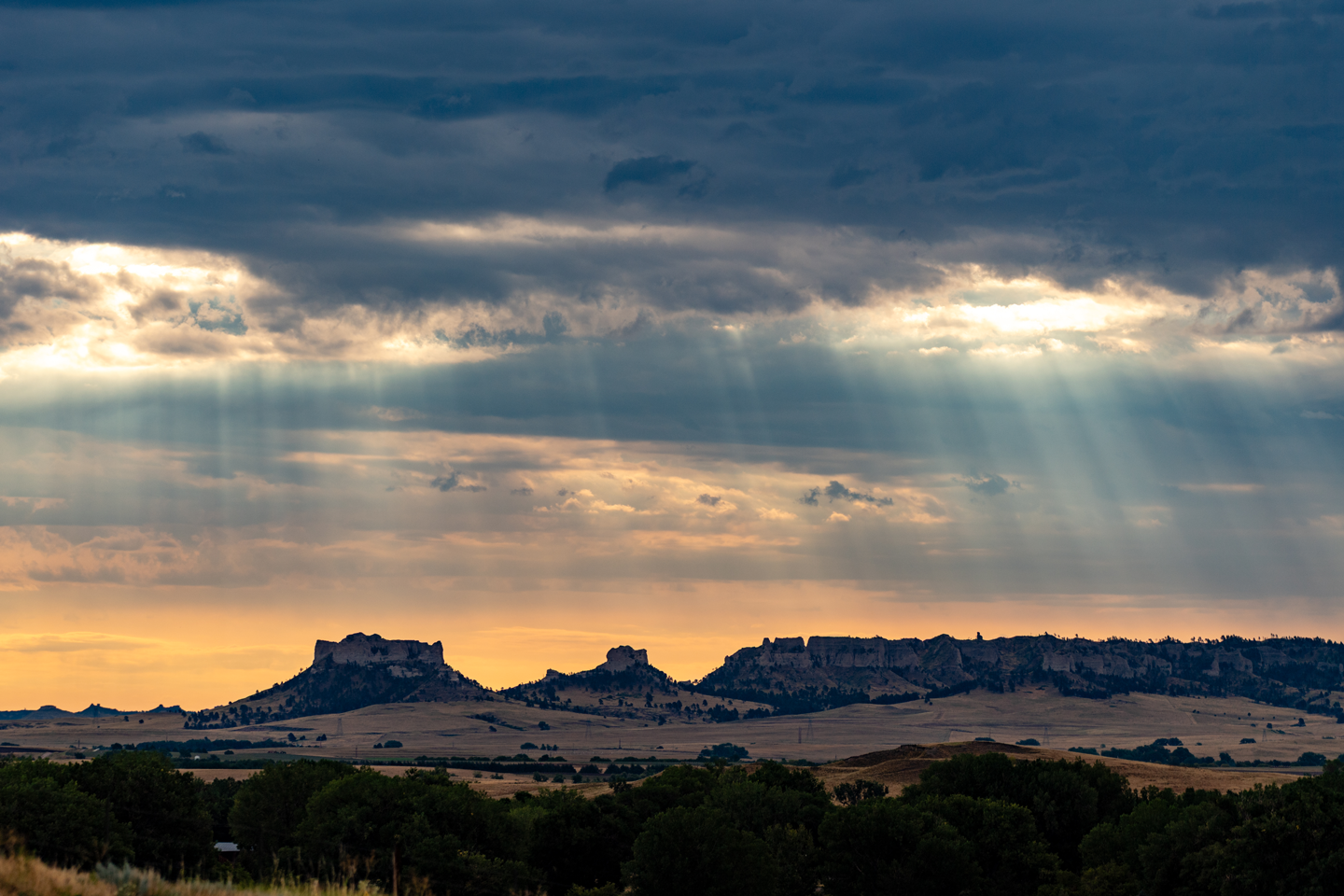 The crepuscular rays of morning grace the sky above Crow Butte and the Pine Ridge.