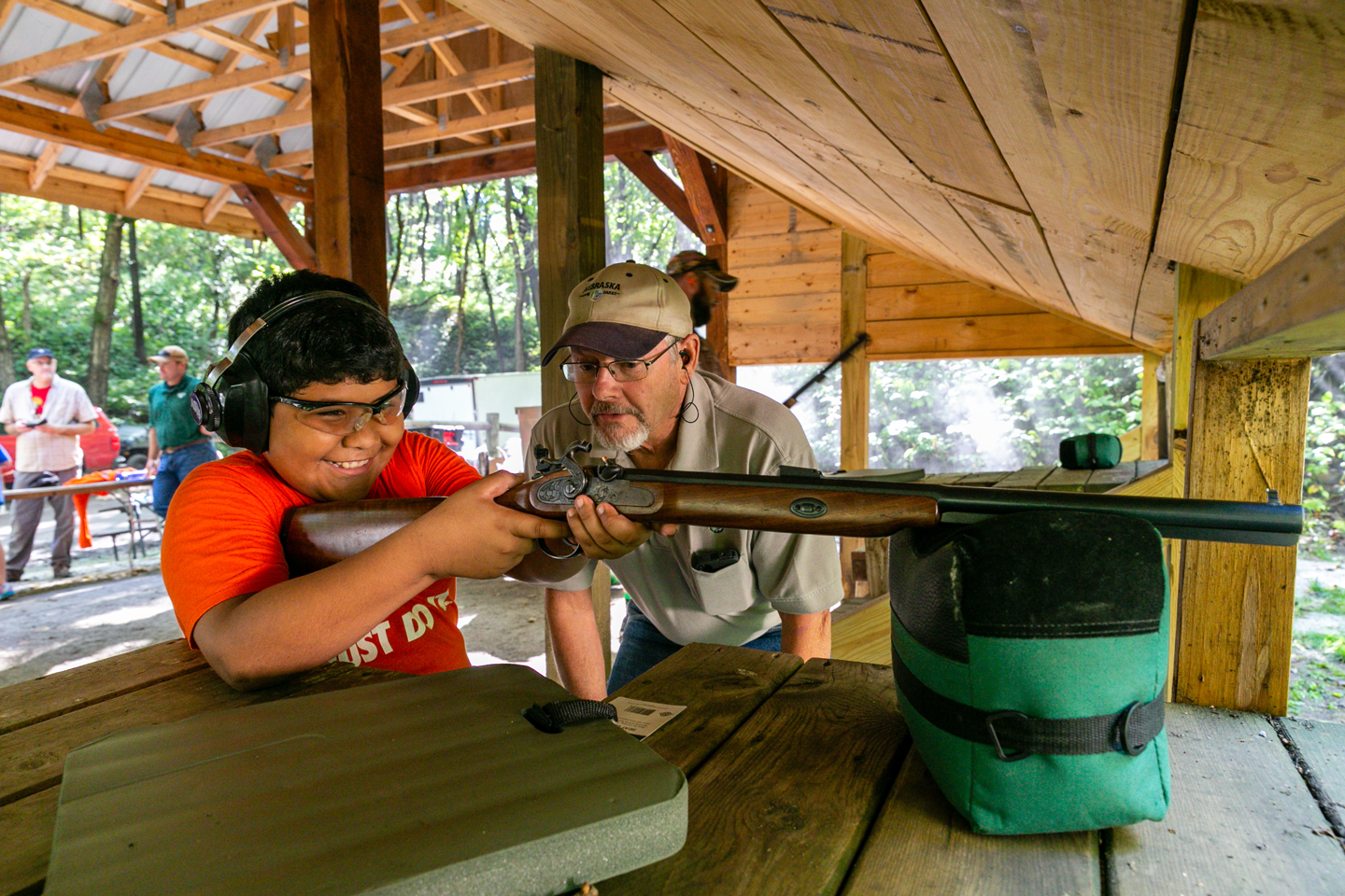Former Nebraska Game and Parks Commission Biologist Tom Welstead teaches a boy how to shoot a muzzleloader.