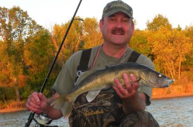 Angler in waders holding a walleye. Photo by Daryl Bauer, Nebraska Game & Parks Commission.
