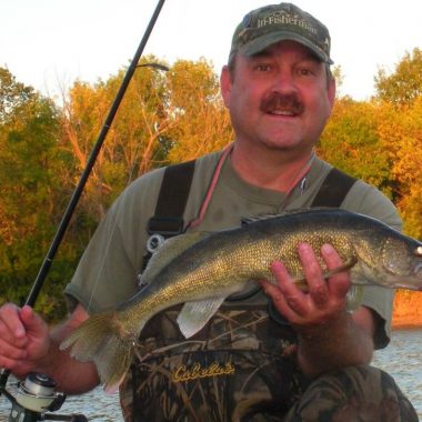 Angler in waders holding a walleye. Photo by Daryl Bauer, Nebraska Game & Parks Commission.