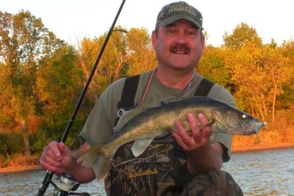 Angler in waders holding a walleye. Photo by Daryl Bauer, Nebraska Game & Parks Commission.