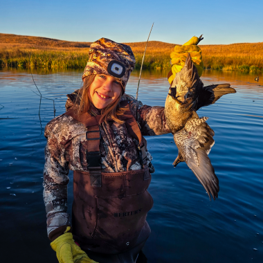 A young girl holds a wood duck while hunting on the Calamus River.