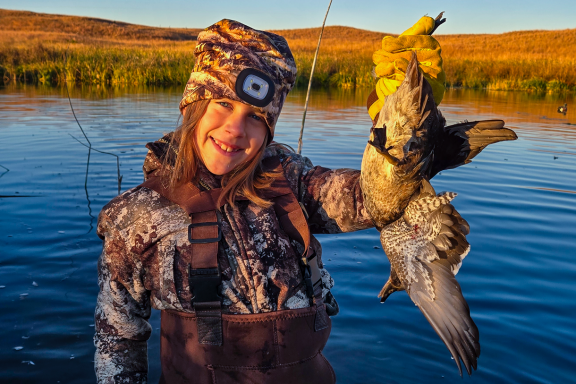 A young girl holds a wood duck while hunting on the Calamus River.
