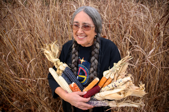 Deb Echo-Hawk of Pawnee, Oklahoma, founded the Pawnee Seed Preservation Society. She is carrying ancestral varieties of corn in her arms.