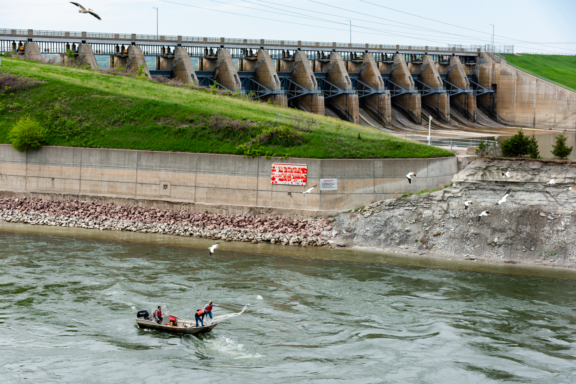 University of Nebraska-Lincoln graduate student Will Radigan pilots a boat as his assistants cast a trawl net to sample larval fish in the spillway below Gavins Point Dam.