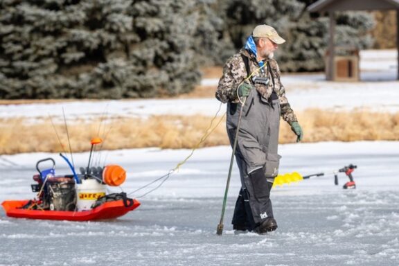 Angler walking on ice with spud bar. Photo by Justin Haag, Nebraskaland Magazine.