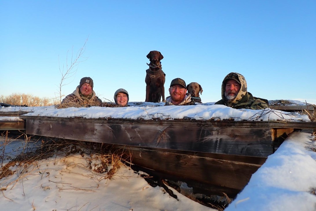 Hunters and dogs looking out of waterfowl blind. Photo by Daryl Bauer, Nebraska Game & Parks Commission.
