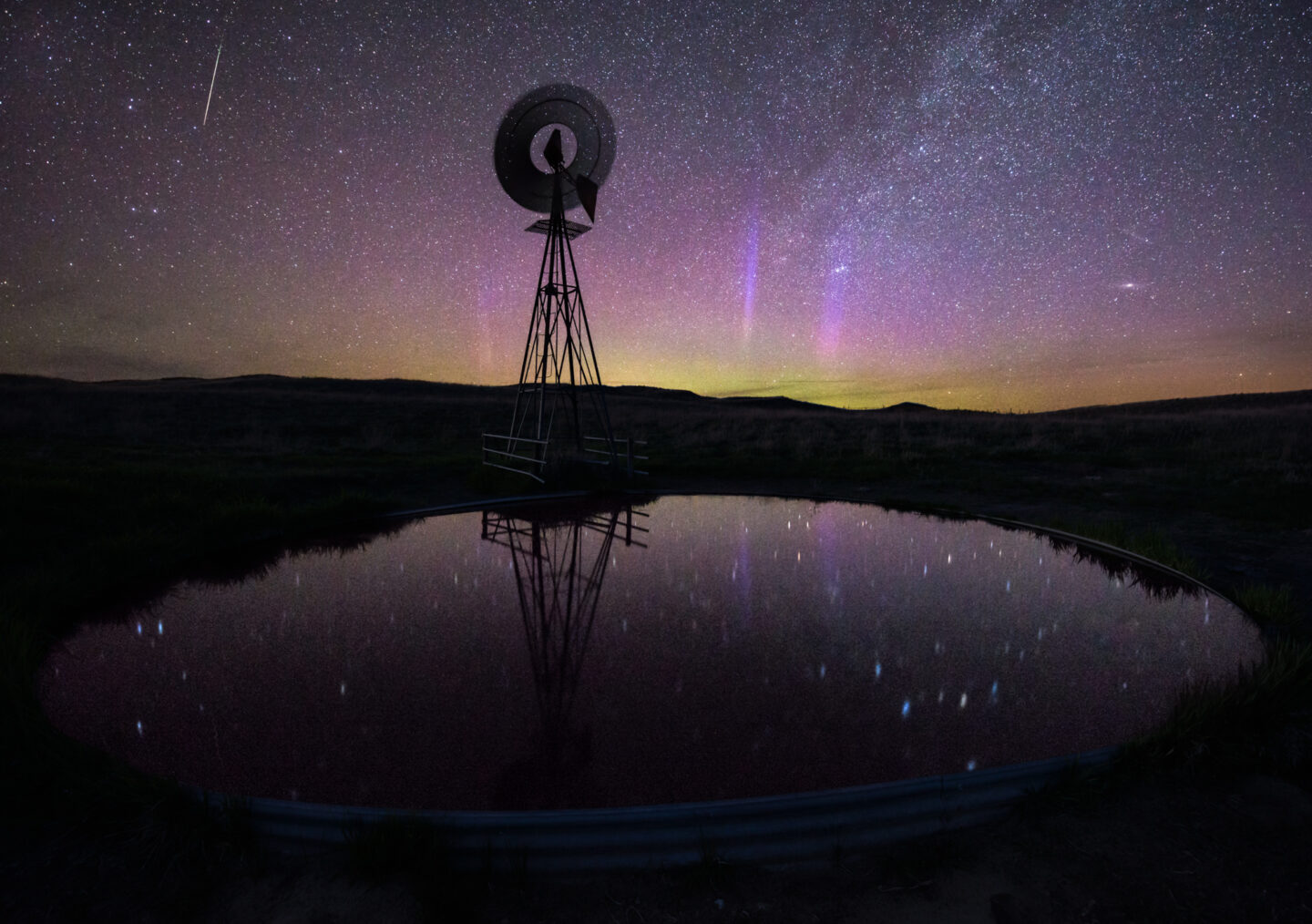 The lights reflect in a windmill stock tank near Valentine. The long camera exposure also captured the movement of the windmill’s blades.