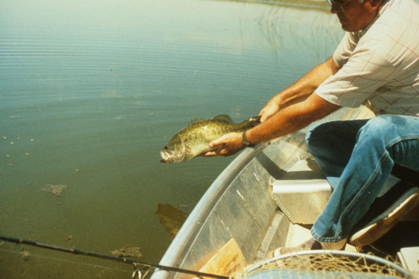 Boat angler releasing a largemouth bass.  Photo by Daryl Bauer, Nebraska Game & Parks Commission.