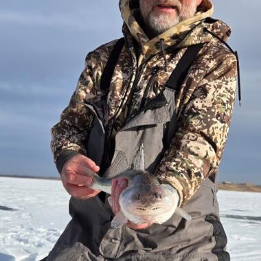 Ice angler holding saugeye. Photo by Emily Brown.