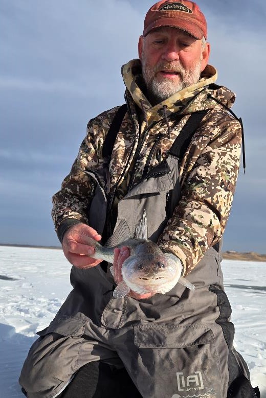 Ice angler holding saugeye. Photo by Emily Brown.