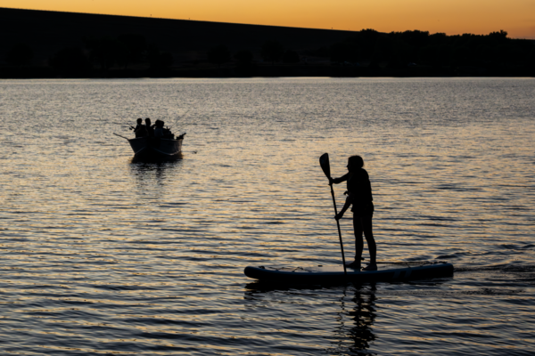 Abigail Martens of Sidney rides a stand-up paddleboard past a boat.