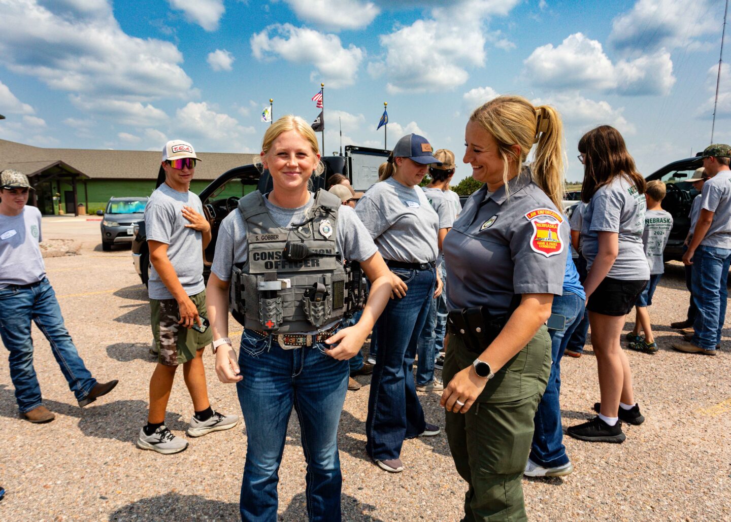 At a Junior Conservation Officer Academy, a student tries on officer Sophia Gobber's ballistics vest. Photo by Julie Gieser, Nebraskaland Magazine.