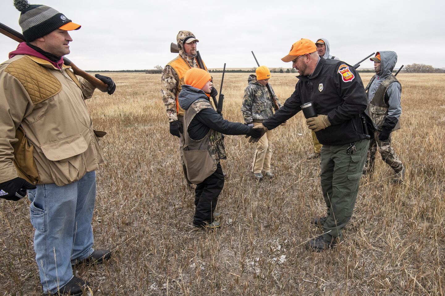 Conservation Officer Kelsey Glodowski interacting with youth pheasant hunters and their dads at Bordeaux Creek Wildlife Managemetn Area (WMA) in Dawes County. Justin Haag, Oct. 24, 2020. Copyright Nebraskaland Magazine/Nebraska Game and Parks Commission.