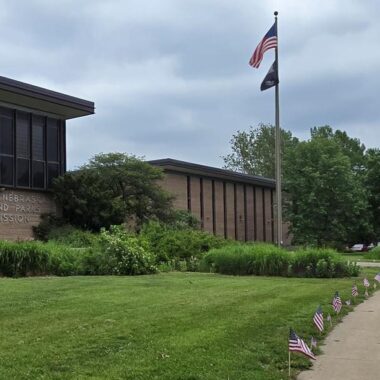 View of Game & Parks Commission headquarters with American flags along sidewalk.