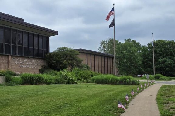 View of Game & Parks Commission headquarters with American flags along sidewalk.