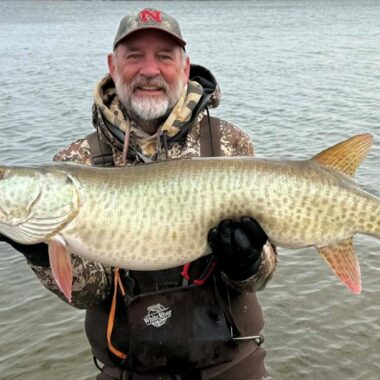 Angler holding muskellunge.