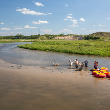 A group of people take a break from tubing on a river in the Nebraska Sandhills.