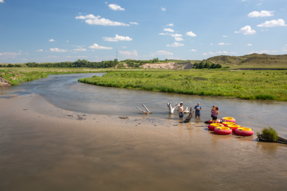 A group of people take a break from tubing on a river in the Nebraska Sandhills.