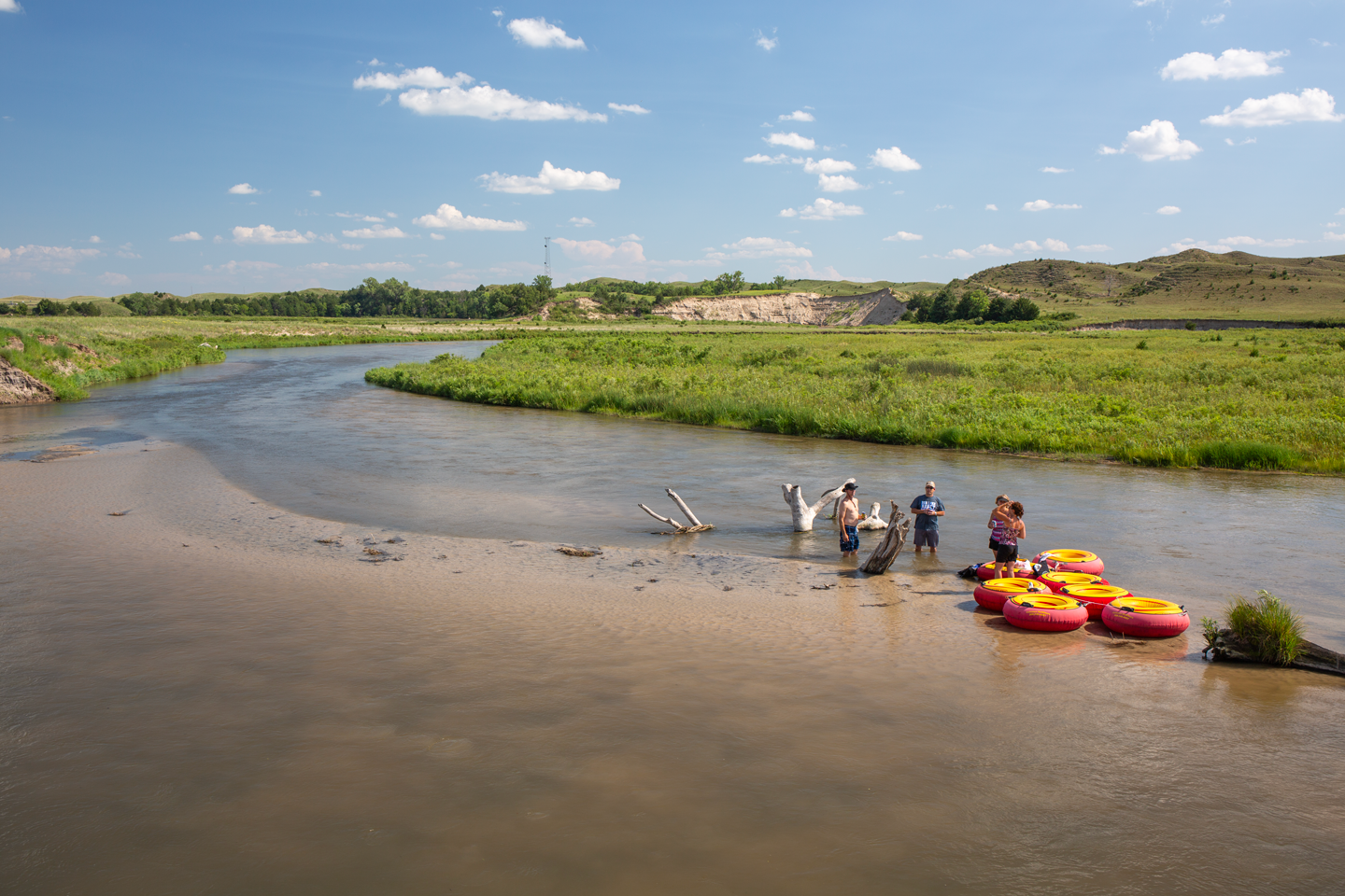 A group of people take a break from tubing on a river in the Nebraska Sandhills.
