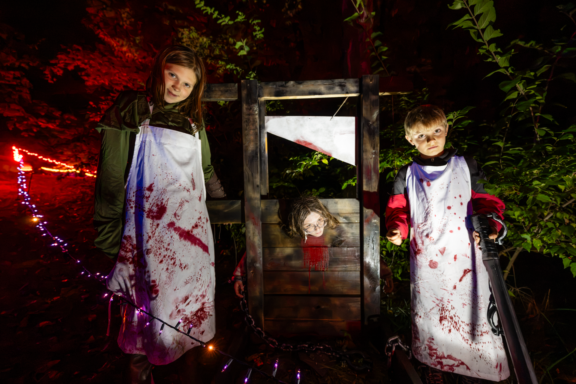 Lorna Thomas, Addison Paul and Layne Wolfe man a guillotine along a haunted walk through the woods in the west campground during the annual Camp Spook Halloween event at Alexandria State Recreation Area.